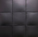 Black padded wall panels arranged in a grid pattern, showing a textured faux-leather or vinyl surface.