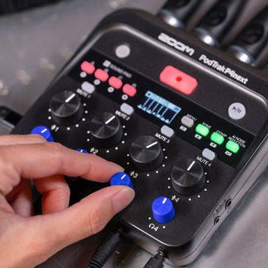 Hand interacting with a Zoom PodTak Plinxt audio device on a blurred background